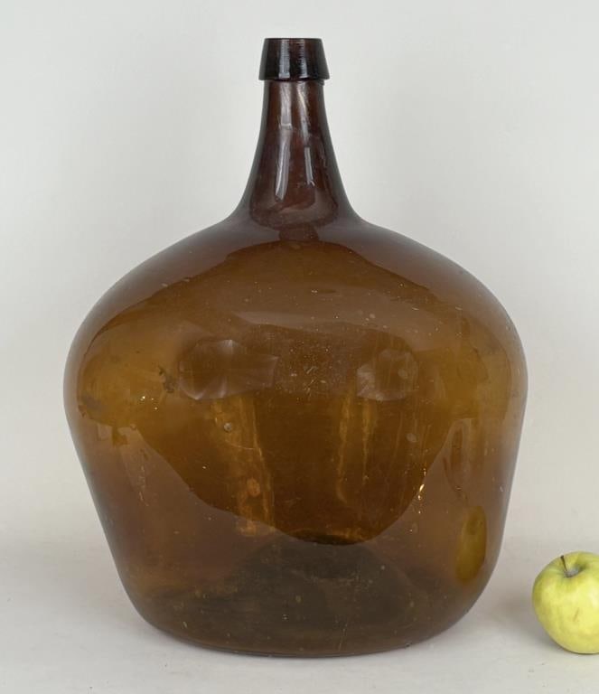Early Large Blown Brown Glass Demijohn Bottle: large slightly ovoid demijohn with deep pontil. 17 1/2" high, 14" wide, 12" deep. Soiling, air bubbles in body. Property from the Estate of Bobbie Hainline Howrey.
