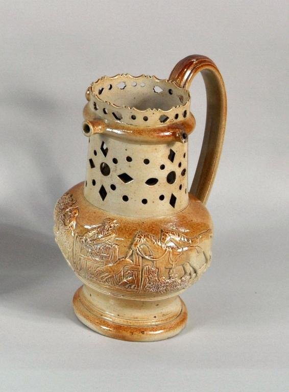 Continental Pottery Puzzle Jug: Continental pottery puzzle stoneware jug with molded scenes of a hunt, 18th/19th C. 8" high, 7" wide, 5" deep.