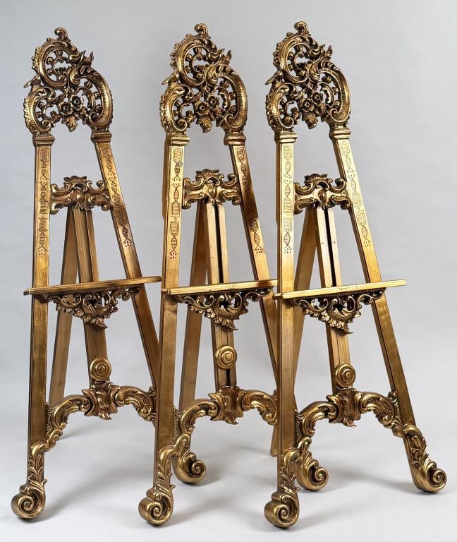 Three Ornate Gold Gilt Art Easels: floral design resin. 68 1/8" high, 28 1/2" wide. Gilt wear, light age and use wear.