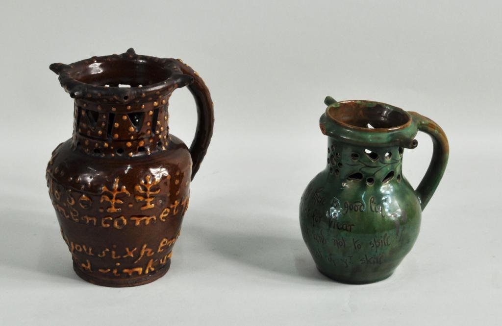 Two English Glazed Pottery Puzzle Jugs, 19th C.: Two English glazed pottery puzzle jugs, 19th C., the larger in mocha lettering on brown ground "1860 Cometh Try Your Skill Gentlemen I'll Hold you Sixpence If You Can't Drink Unless You..."; together 