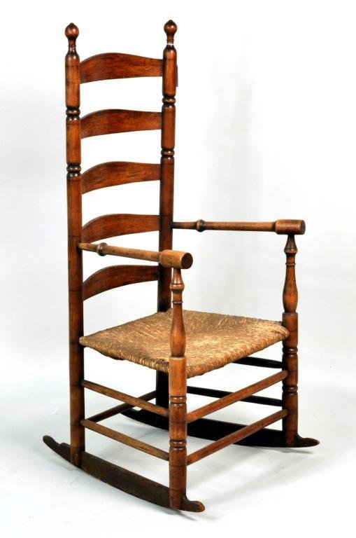 New England Maple Ladderback Rocking Chair: New England maple ladderback rocking chair, 19th C., with turned arms and stiles, hickory back rails on rush seat. 46"hgh, 22" wide, 16" deep. Condition: finish wear, loss, stains, break to one seat r