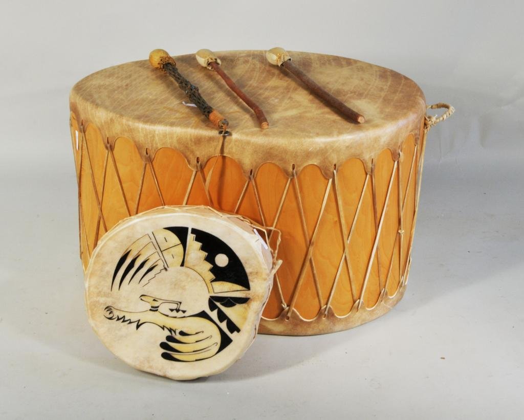 Two Taos Cottonwood & Hide Drums: Two Taos cottonwood and hide drums and three drumsticks, 20th C., comprising: a large floor drum and a hand drum with painted decoration. Largest: 19 1/2" high, 29" long; smallest: 3" high, 14" wide. 