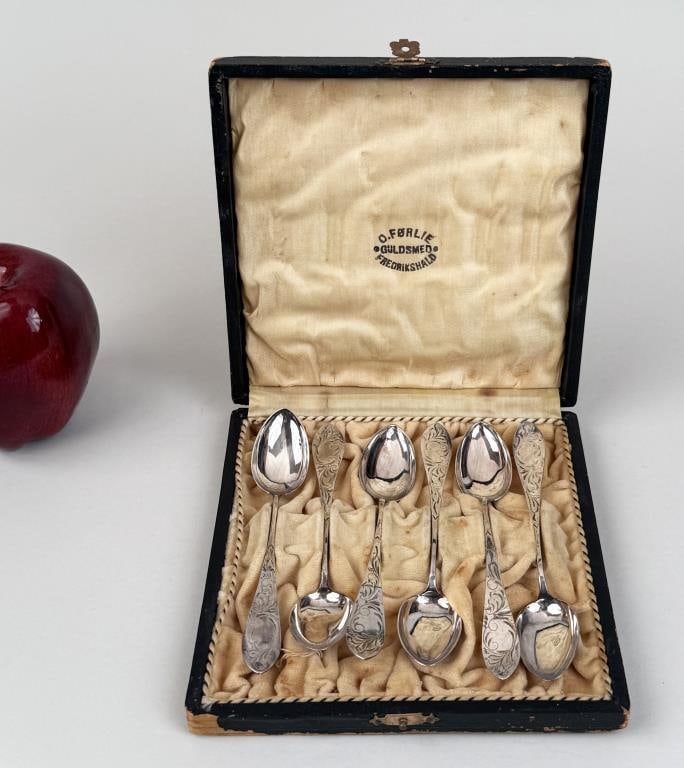 O. Forlie .830 Silver Cased Spoon Set: with intricate engraved design. 5 1/4" long. Weight: 1.825 OZT. Light age and use wear; box with soiling, losses. *No credit card payments will be accepted for silver, gold, or jewelry from buyers tha