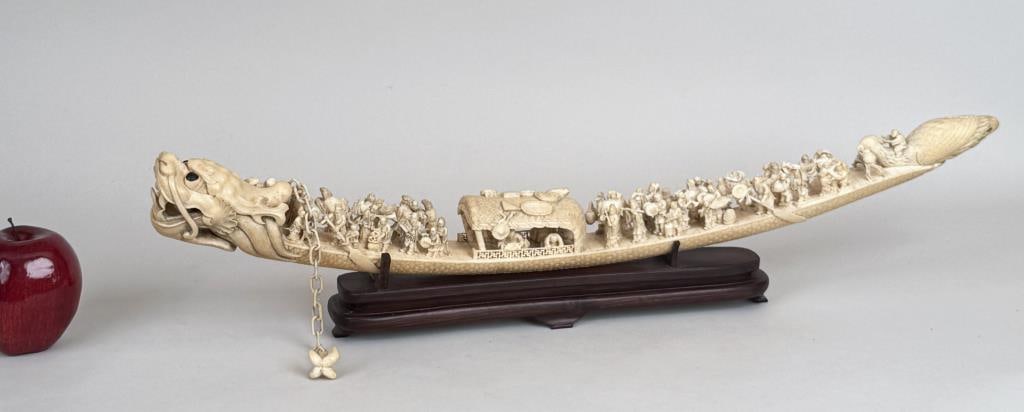 Chinese Carved "Happy Boat": intricately carved dragon vessel with pendant chain anchor; the head forming the prow and enclosing a free floating ball in its mouth, the scaled body carrying numerous figures and center pavilion ter