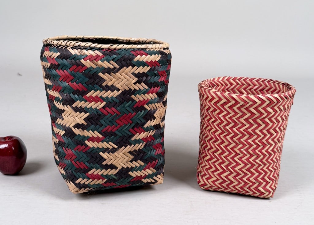 Two Chocktaw Native American Baskets: one with card from The Mississippi Crafts Center, cards indicate maker Charlie Tomhatta and native swamp cane as the material. Largest: 12 1/2" high, 10 3/8" diameter. Age and use wear.