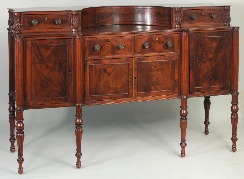 Thomas Seymour School, Boston Sheraton Sideboard: Very fine Sheraton carved mahogany sideboard, with rectangular form having concave entablature above a case with two drawers over two cabinet doors, flanked by two end cabinet doors, with reeded stile