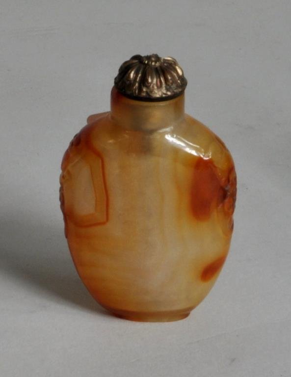 Carnelian Agate Snuff Bottle: Carnelian agate snuff bottle, of flattened ovoid form with mask form lugs and repousse brass stopper. 2 3/8" high, 1 1/2" wide.