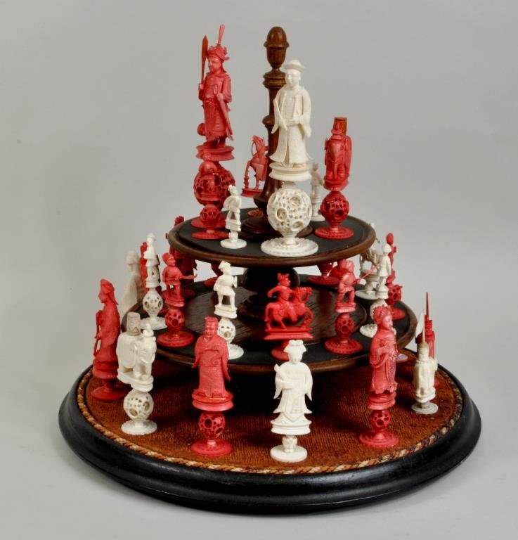Chinese Carved Ivory & Stained Chess Set: Chinese carved and stained ivory chess set, circa 1900, mounted on display stand with glass dome. Pieces 2 3/4" high, 1 1/8" diameter to 6" high, 1 1/2" diameter. Condition: pieces glued to stand. NO