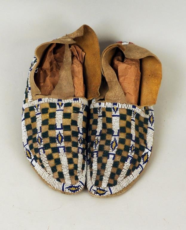 Pair of Plains Moccasins: Pair of Plains moccasins, 19th/20th century, with green, blue, yellow, white and red geometric beadwork, 10 1/4" long, 4" wide. Condition: soiling.