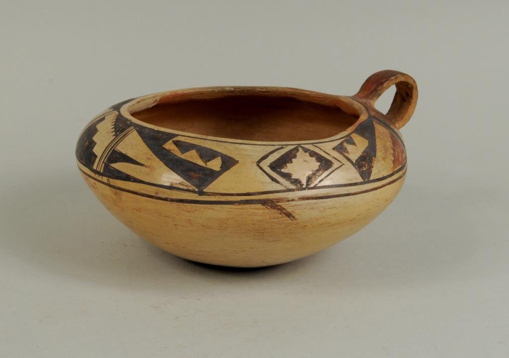 Hopi Handled Pot: Hopi handled pot, 20th century, with geometric rim designs in red and brown on a cream ground. 3 1/4" high, 6 3/4" wide. Condition: a few small chips.