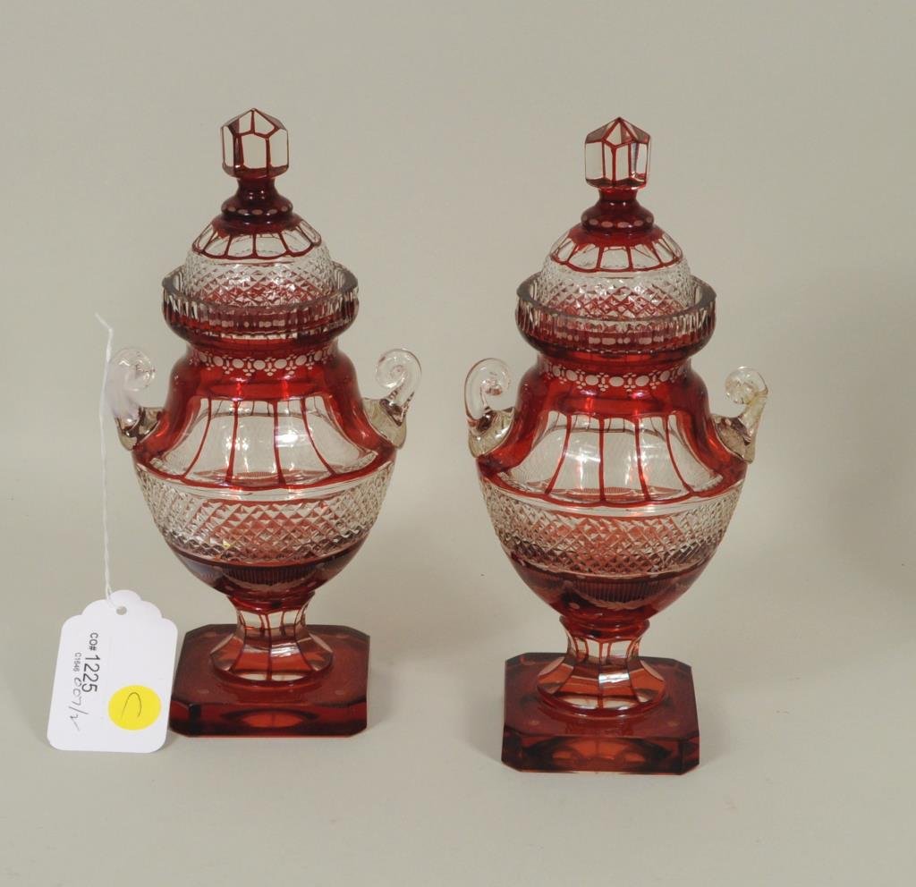 Pair Early Cranberry Lidded Cut Glass Urns: Pair early cranberry lidded cut glass urns, probably by Greenpoint Glassworks, Brooklyn, New York, circa 1861. Designed and cut by Christian Dorflinger. 9" high, 4 5/8" wide. Condition: one with lid c