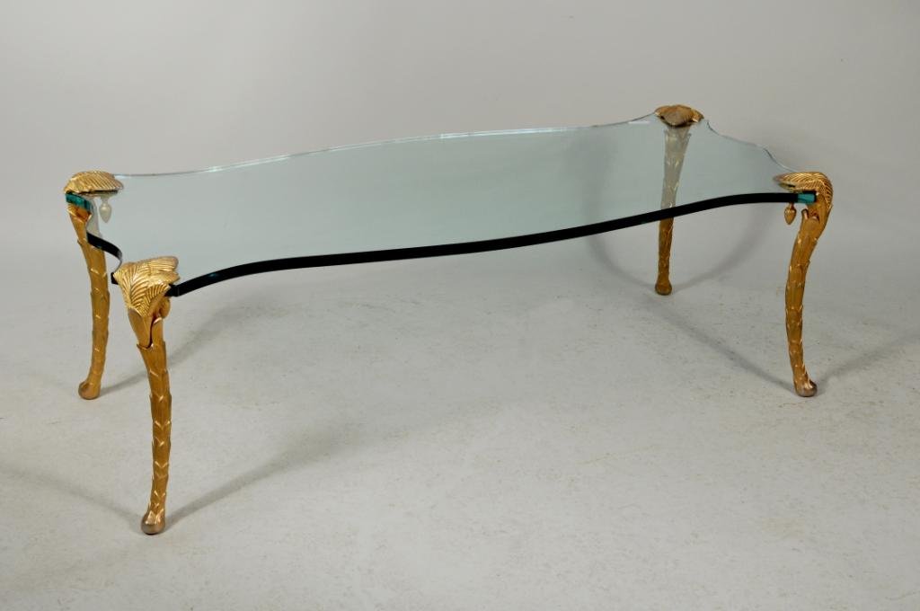 Glass Coffee Table with Shaped Top: Glass coffee table with shaped top, gilt metal leaf form legs. 17" high, 21 1/4" wide, 52" long. Condition: chips to glass. Includes two additional legs.