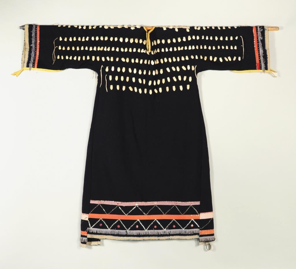 Crow Woman's Elk Tooth Wedding Dress: Crow woman's dress, made from blue wool trade cloth with hand sewn rows of carved "elk" bone and ivory teeth front and back, sleeves and hem with applied ribbon, sequin and fringe detail. According to
