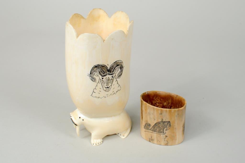 Two Inuit Scrimshaw Walrus Ivory Containers: Two Inuit scrimshaw walrus ivory containers comprising a scalloped vase with walrus base signed "Lorvis Ozenn?" and a fossil ivory container signed "Ed Penotoe". 1 3/4" high, 1 7/8" wide to 5" high, 2