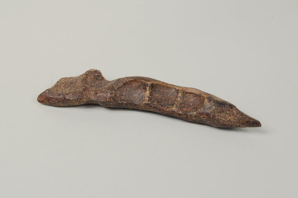 Inuit Carved Whip Handle of Fossilized Material: Inuit carved whip handle of fossilized material used for driving dogsleds. It was found in Ev'wok west of Savoonga, a town destroyed by a volcanic eruption. 6 1/2" long, 1 1/4" wide.