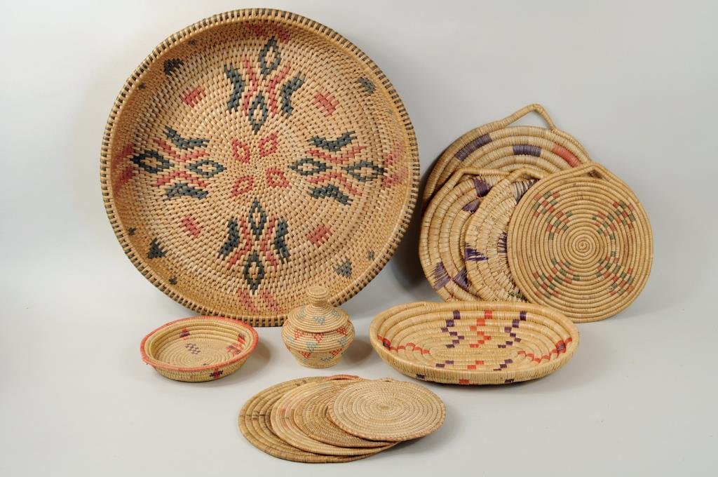 Twelve Inuit Grass & Reed Baskets & Plaques: Twelve Inuit grass and reed baskets and plaques including a small covered basket and large reed basket. 3 3/4" high, 3 1/4" wide to 2 1/2" high, 15" diameter.