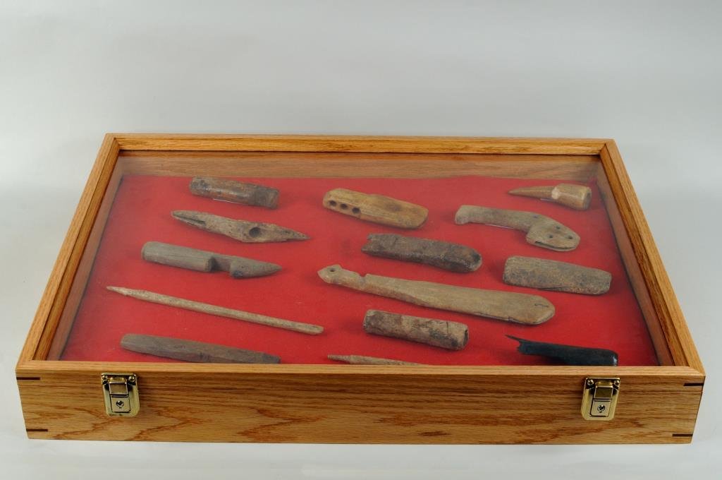 Group Early Inuit Ivory Wood & Bone Tools: Group of early Inuit ivory wood and bone tools including four adze handles and a knife handle from the Brevig Mission area, two awls, two drum handles, a toggle, harpoon head and other items in a wood