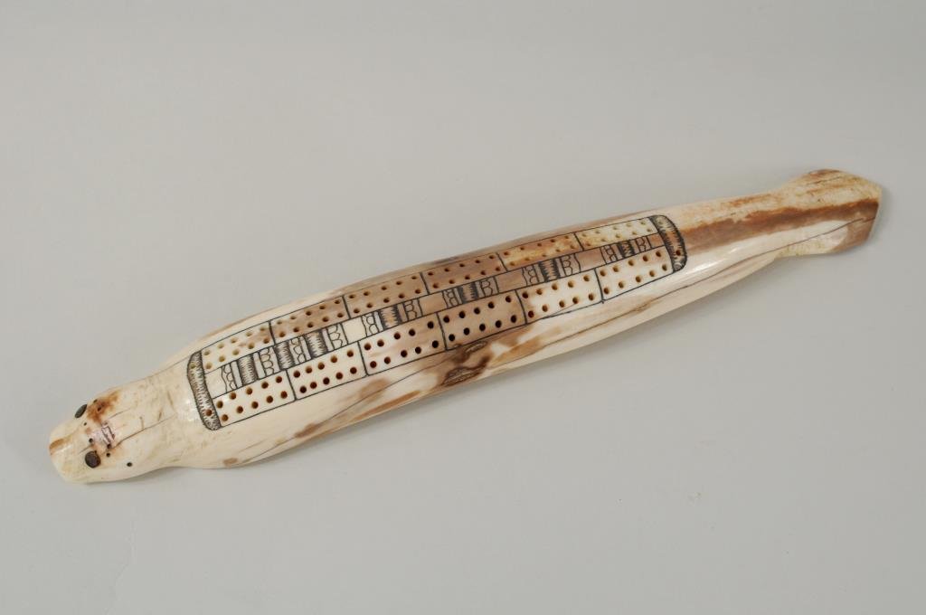 Inuit Scrimshaw Seal Cribbage Board: Vintage Inuit scrimshaw seal form walrus tusk cribbage board with baleen inlaid eyes.11 1/2" long, 1 3/4" wide. Condition: age cracks. International clients are ineligible to bid on this item. It is f