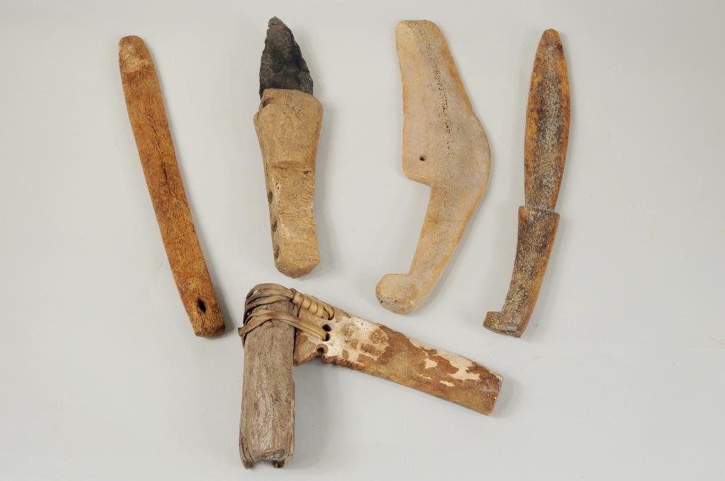 Five Early Inuit Bone Tools: Five early Inuit bone tools comprising: three snow knives and two adzes from the Brevig Mission area. 6 1/4" long, 4 1/4" wide to 9 5/8" long, 2 3/8" wide. Condition: adze with slate blade: handle and