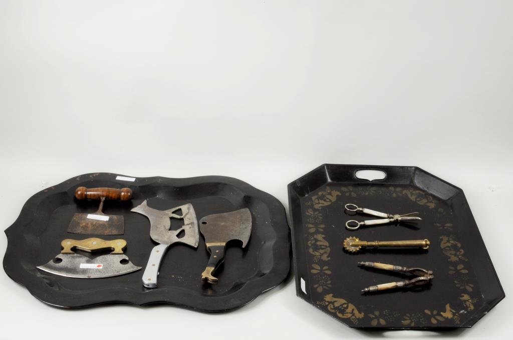 Seven Antique Kitchen Implements w/Two Tole Trays: Seven antique kitchen implements including a figural fox cleaver, a boot handled cleaver, two choppers and other implements, together with two tole trays. 7" long, 2" wide to 18" high, 24 1/2" wide. C