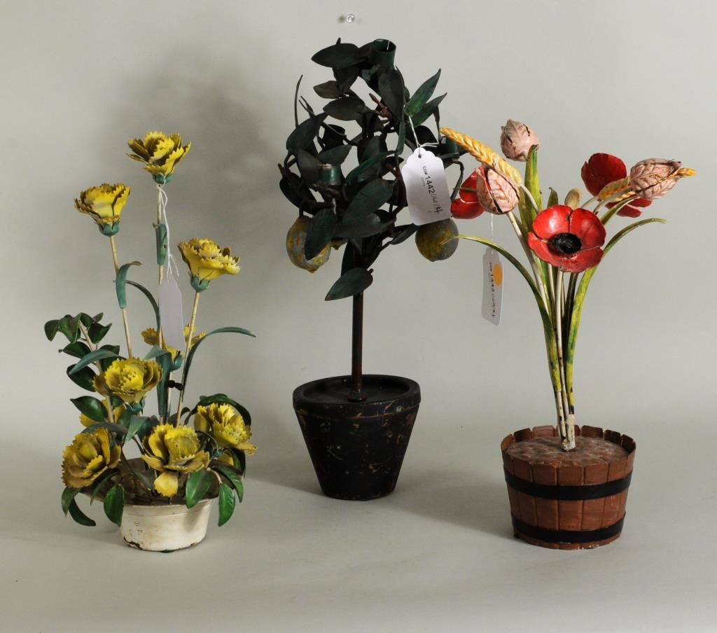 Three Tole Painted Floral Groups: Three tole painted metal floral groups comprising carnations, poppies and a lemon tree. 10 3/4" high, 14 1/2" wide to 17 1/2" high, 8" wide. Condition: soiling, paint loss, bends.