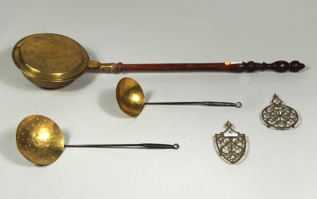 Five Antique Brass Household Items: Five antique brass household items comprising a bedwarmer, skimmer and ladle and two trivets stamped "Norwich CT". Largest: 44" high, 11 1/2" wide. Smallest: 7 3/4" high, 4" wide. Condition: use wear,