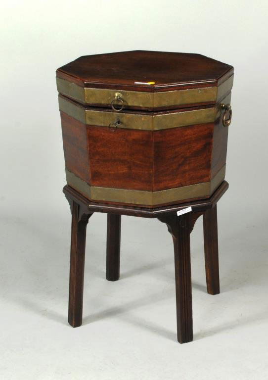 George III Mahogany Octagonal Wine Cellarette: George III mahogany octagonal cellarette, brass bound, the lift top opening to a fitted interior, on a conforming molded stand. 29 1/2" high, 18" wide, 18" wide. Condition: the base originally with ca