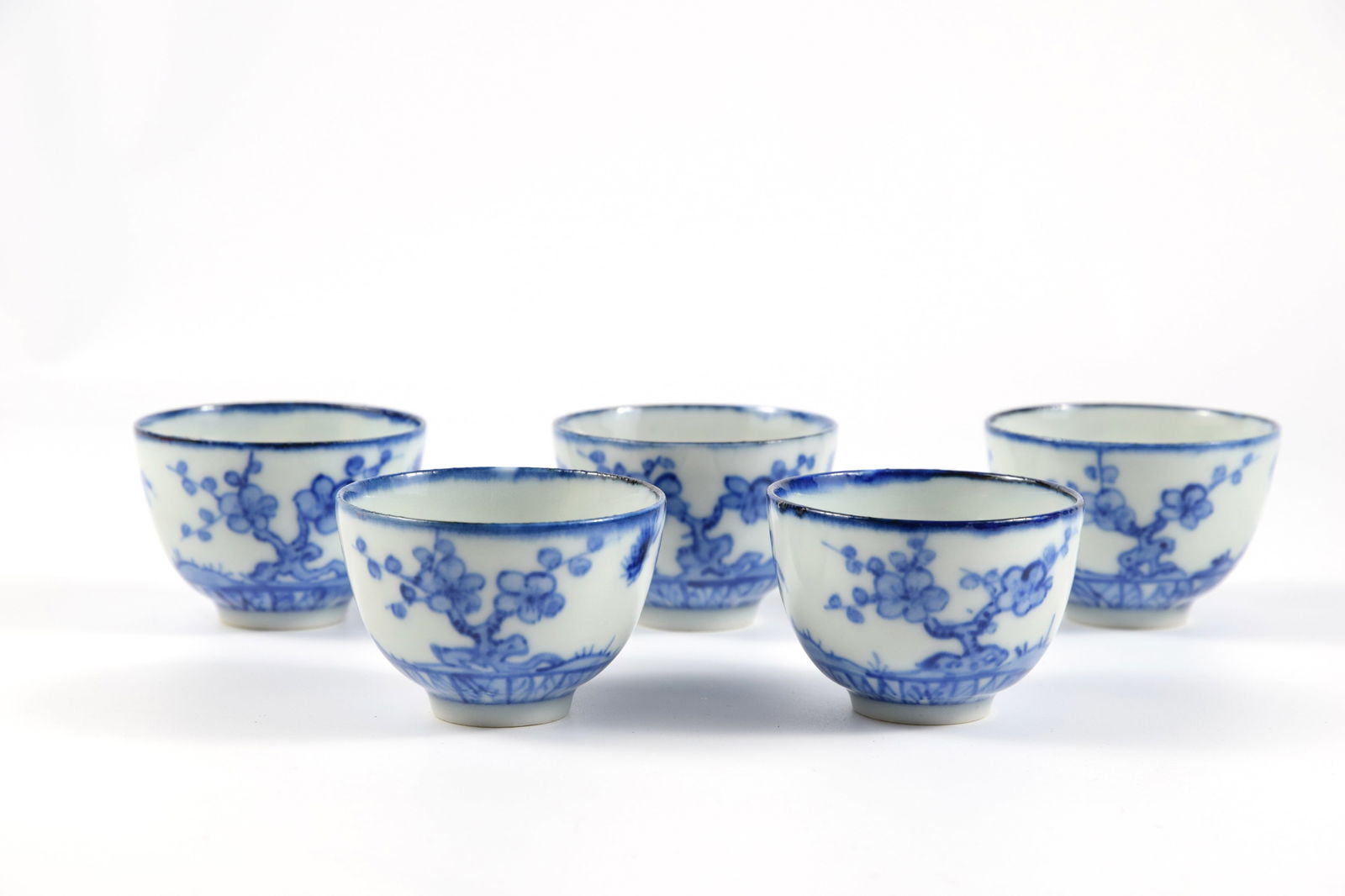 Yohei Seifu IV: Set of 5 Blue and White Teacups: A graceful set of five tea cups by Seifu Yohei IV, delicately rendered in sometsuke with the revered motifs of pine, bamboo, and plum—symbols of perseverance, resilience, and renewal. The fluid coba