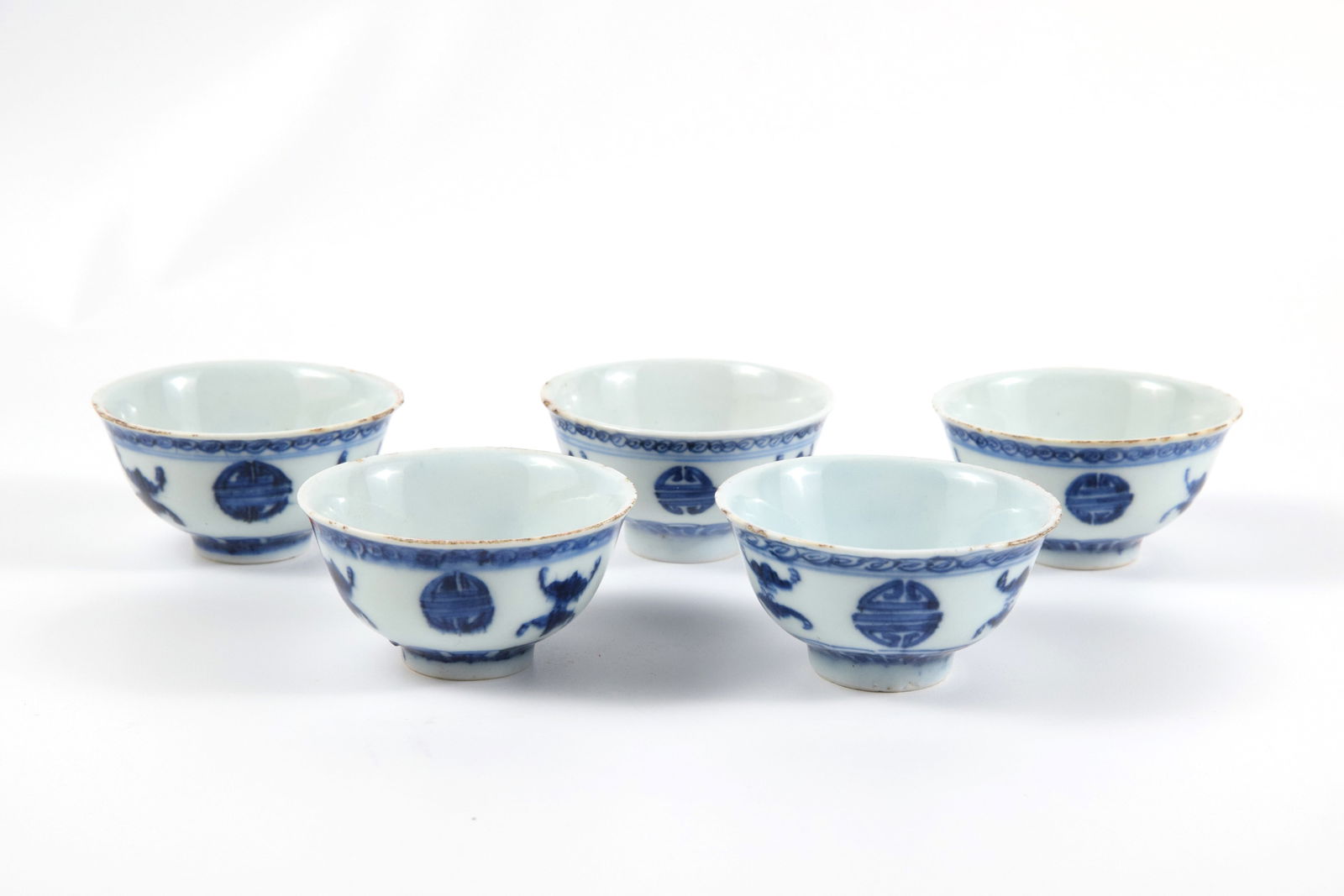 Set of 5 Blue and White Teacups: A refined set of five blue and white porcelain tea cups, elegantly painted with auspicious motifs in rich cobalt underglaze. The rhythmic arrangement and lustrous glaze capture the timeless charm of c