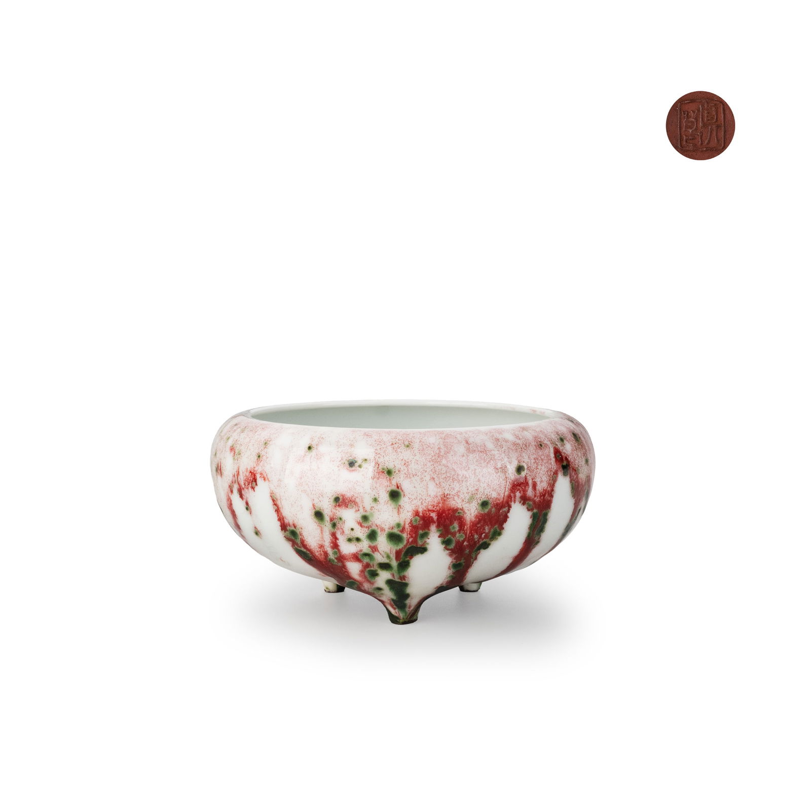 Cinnabar-Glazed Tripod Censer by Makuzu Kozan: A tripod incense burner covered in a thick cinnabar [shinsya] glaze, the rounded body rising from three short feet. The creamy white ground is dramatically suffused with flowing red tones and irregula
