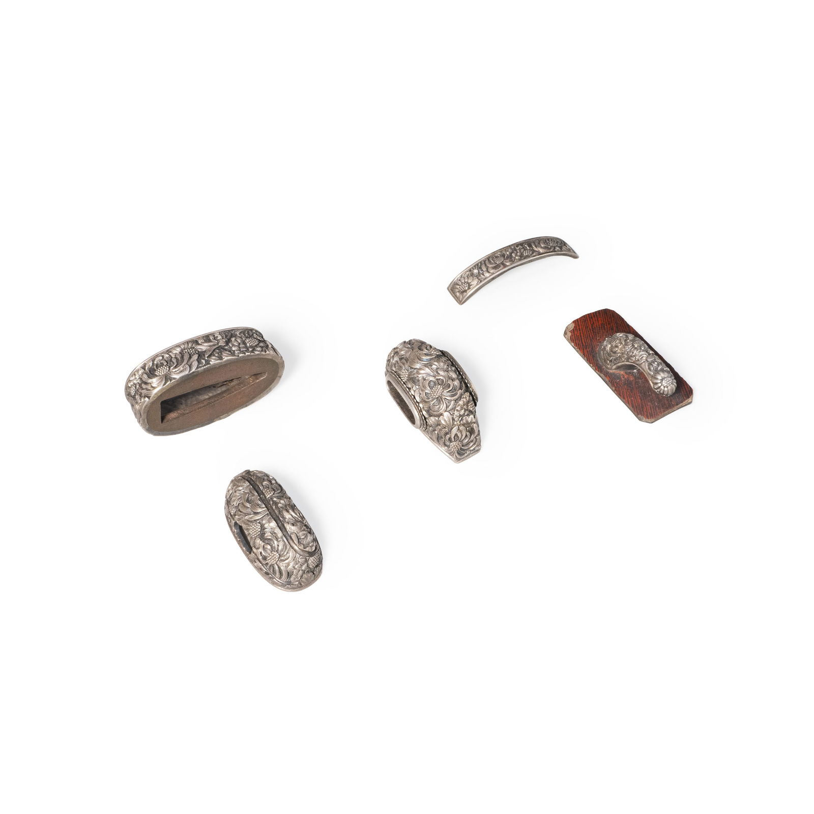 Silver sword fittings: A matched group of Japanese sword fittings crafted in silver, finely decorated with continuous floral scroll motifs. The set includes multiple components, each carefully worked in low-relief carving,