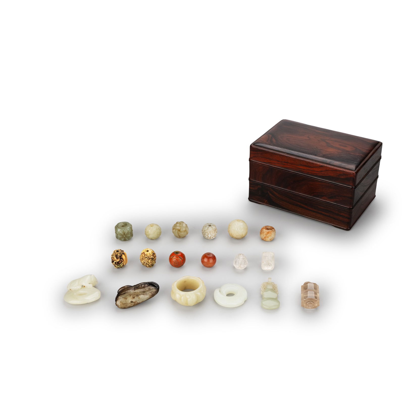 12 Ojime & 6 Pendants, with Case: The assortment features a varied palette and materials, including pale stone-like beads, clear examples, red-toned beads, and gilt metal carved beads. Forms range from spherical and barrel shapes to