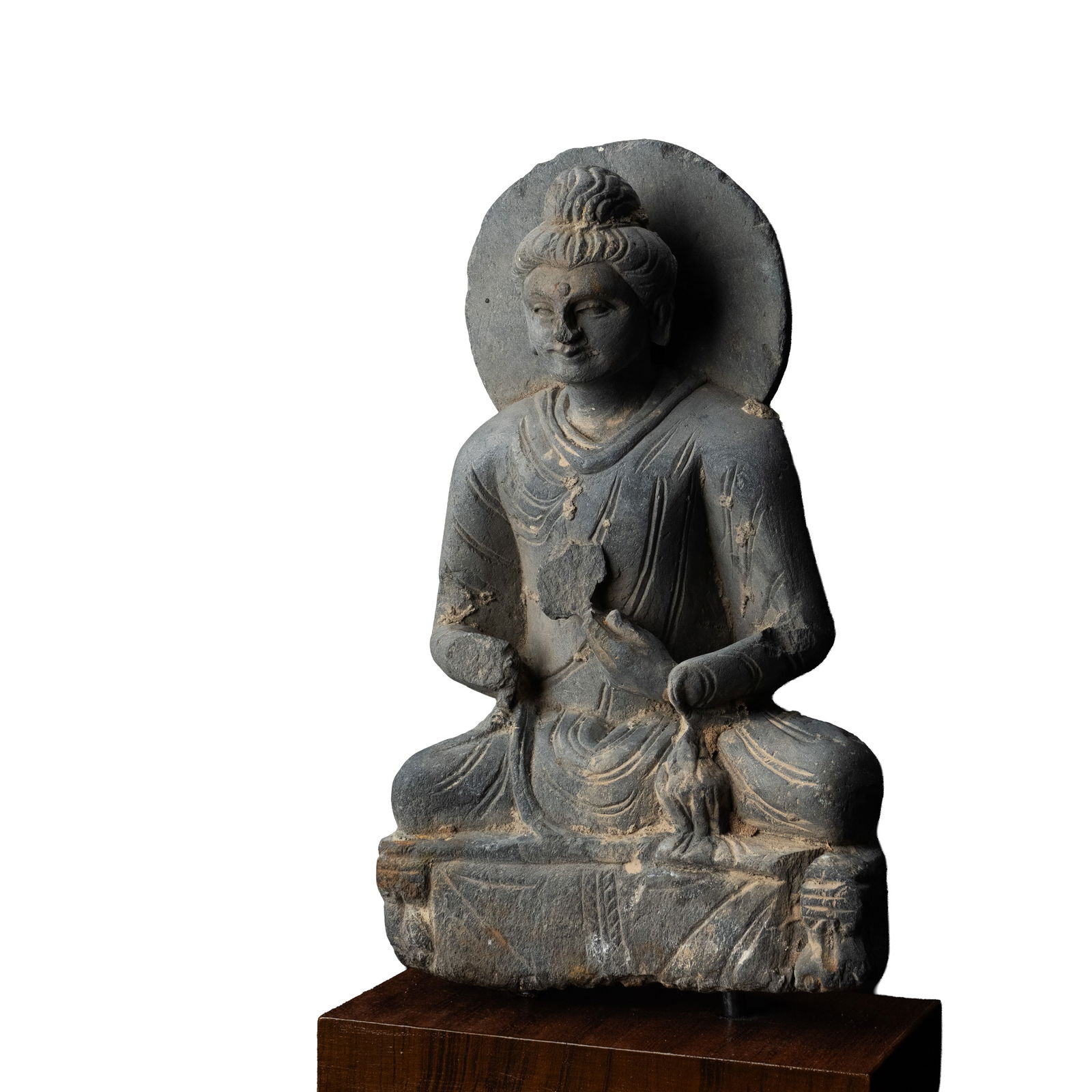 Gandhara Sculpture with Certificate by Kurita Isao: Carved in grey schist, this seated Buddha is shown cross legged upon a rectangular plinth, backed by a circular halo. The figure presents a serene countenance with softly modeled features, almond shap