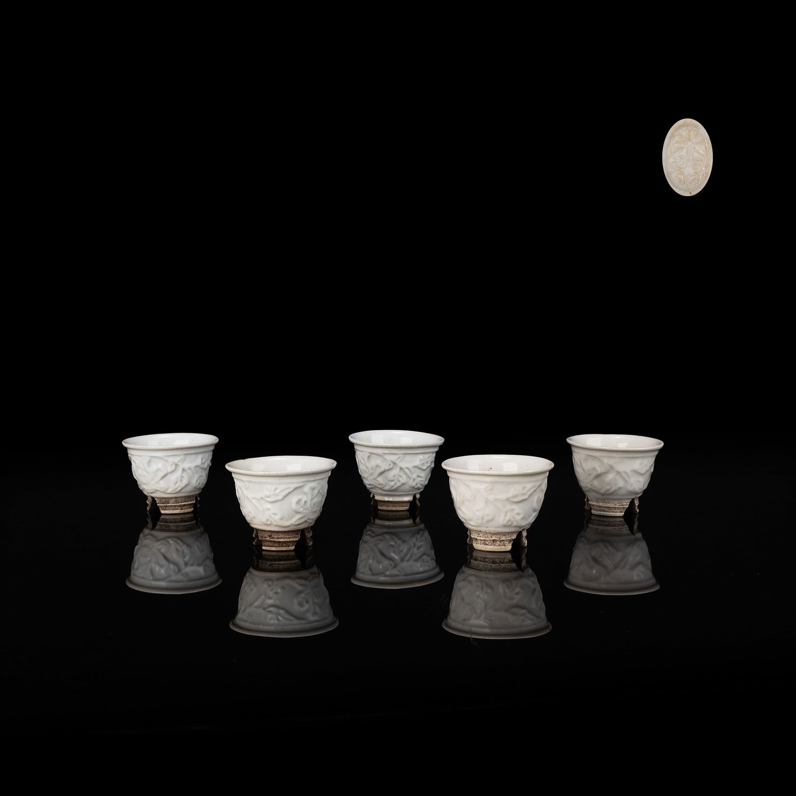 5 White Porcelain Tea Bowls by Aoki Mokubei: A refined set of five white porcelain tea cups decorated with molded floral motifs in low relief. The crisp white glaze enhances the subtle shadows of petals and leaves, creating an elegant and