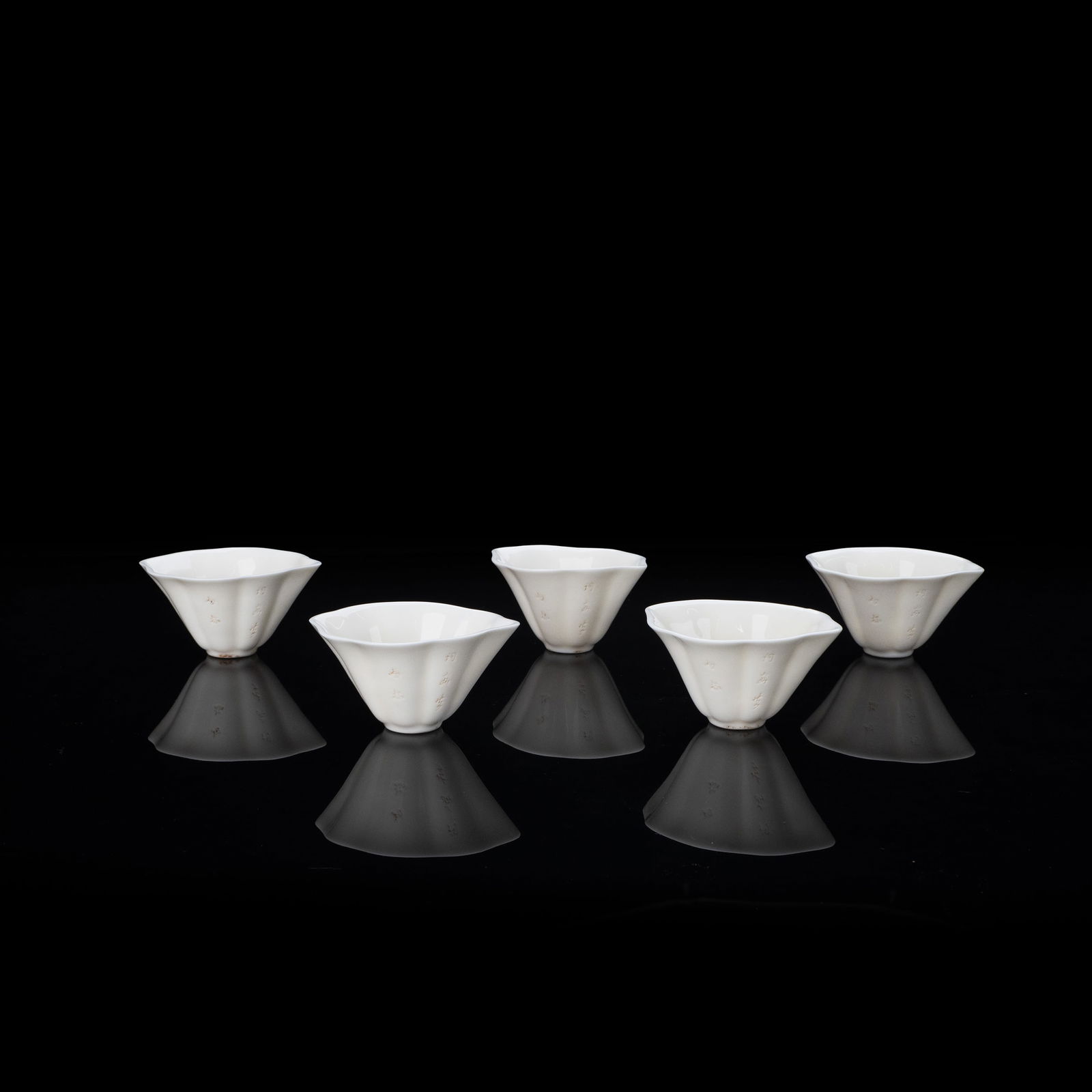 Set of 5 White Porcelain Sencha Tea Bowls from Deha Kiln: This set comprises five white porcelain tea bowls produced at the Dehua kiln. The rims are shaped like petals, and the overall forms feature gentle undulations, reflecting a refined and balanced