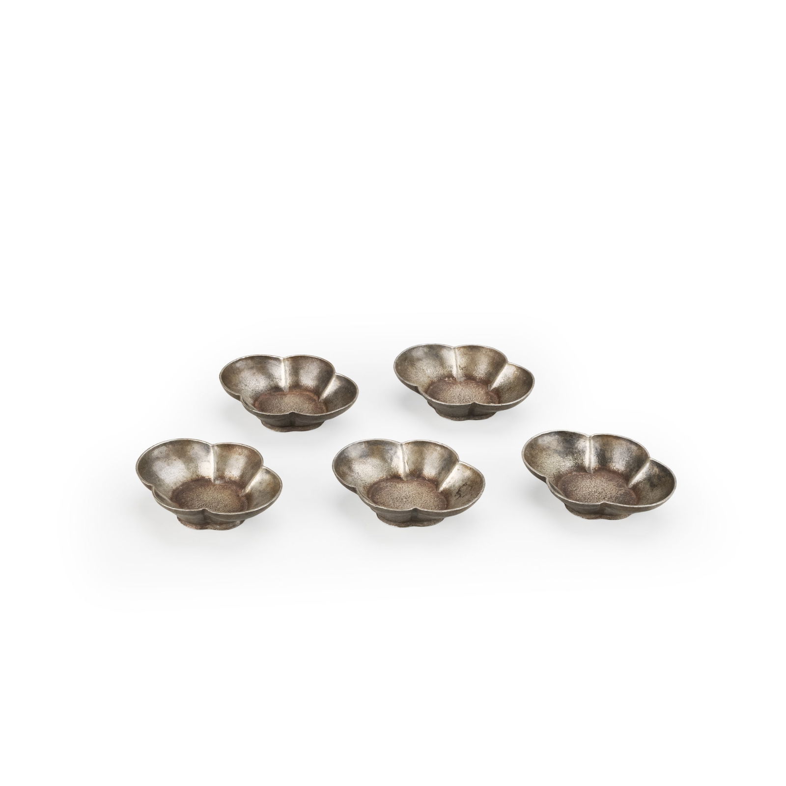 A Set of Five Antique Pewter Tea Saucers, Mokko Shape: A set of five antique tin tea saucers, each formed in a mokko shaped outline. The gently lobed rim creates a refined floral silhouette, while the shallow well is subtly recessed to accommodate a tea