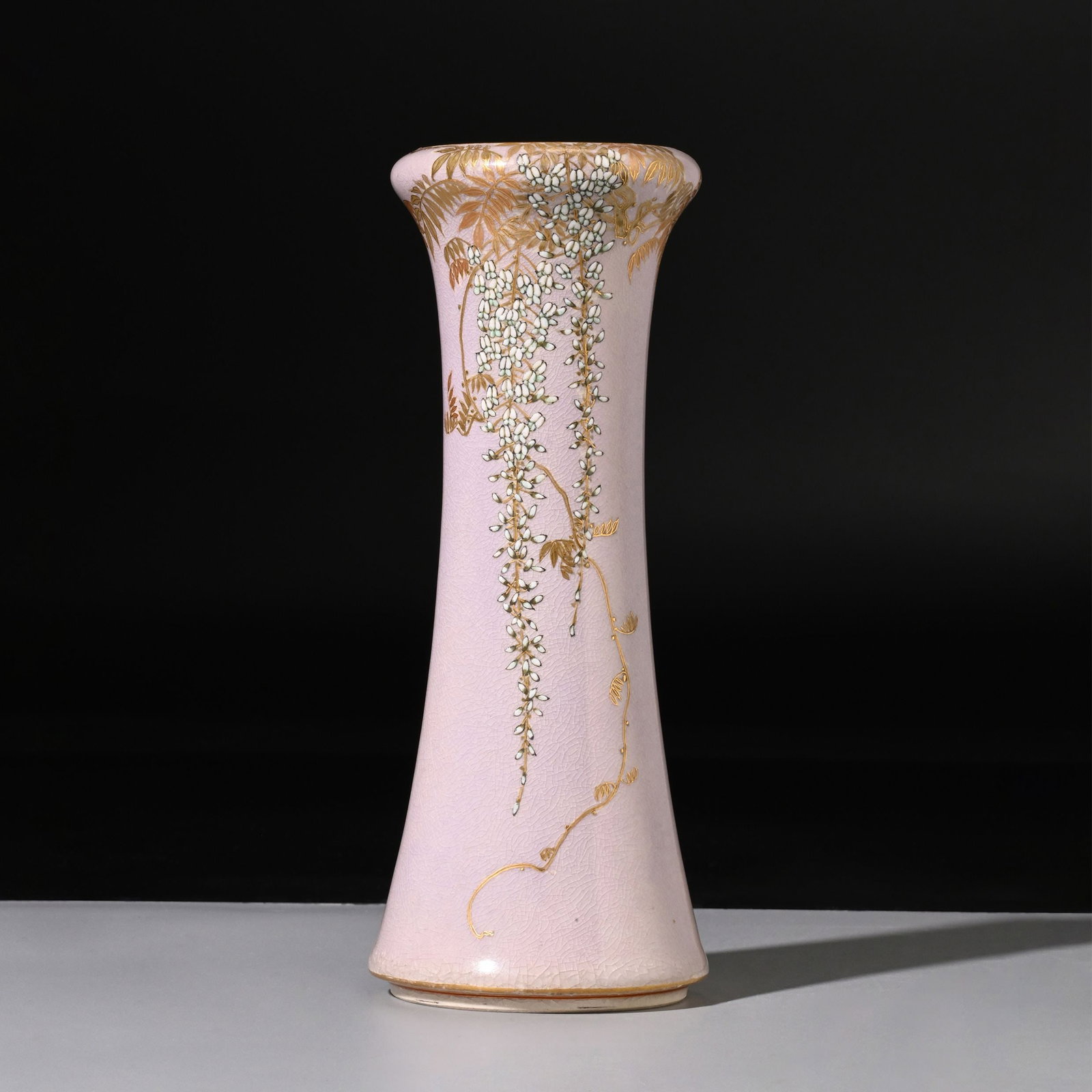 Vase by Yabu Meizan: Elegantly potted with a gently flared mouth and tapering body, this Satsuma vase is decorated with cascading clusters of wisteria delicately rendered in gilt and enamel against a soft pale-pink crackl