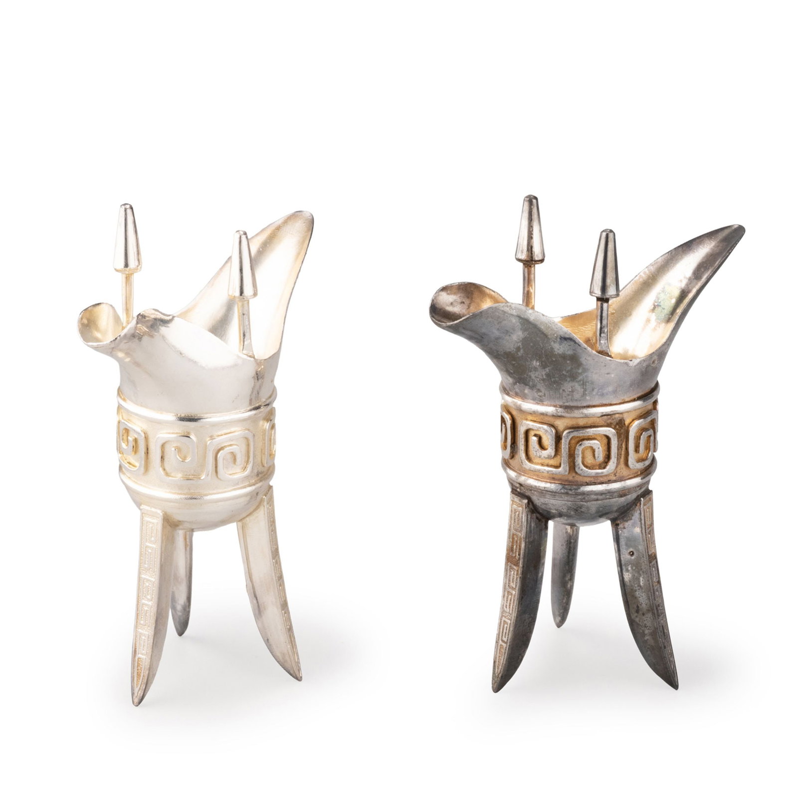 Pair of Silver Jue with Tiancheng Mark: This elegant pair of silver jue-form vessels is inspired by the celebrated ancient Chinese bronze jue, faithfully incorporating its distinctive pouring spout, tail, twin finials, and three splayed leg