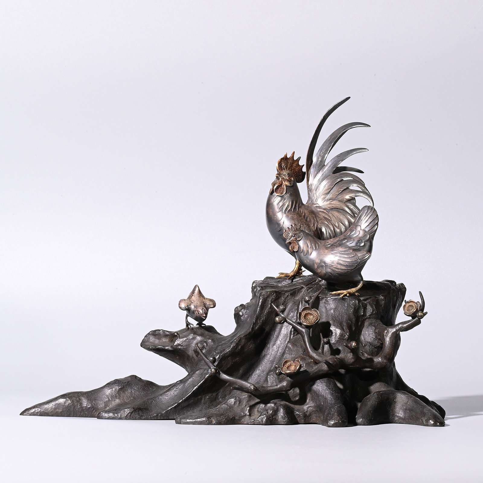 Silver Chicken Ornament by Jusei: Depicts a rooster, a hen, and a chick gathered upon an aged tree stump with blossoming plum branches, creating a lively and harmonious scene inspired by nature. The carefully balanced composition comb