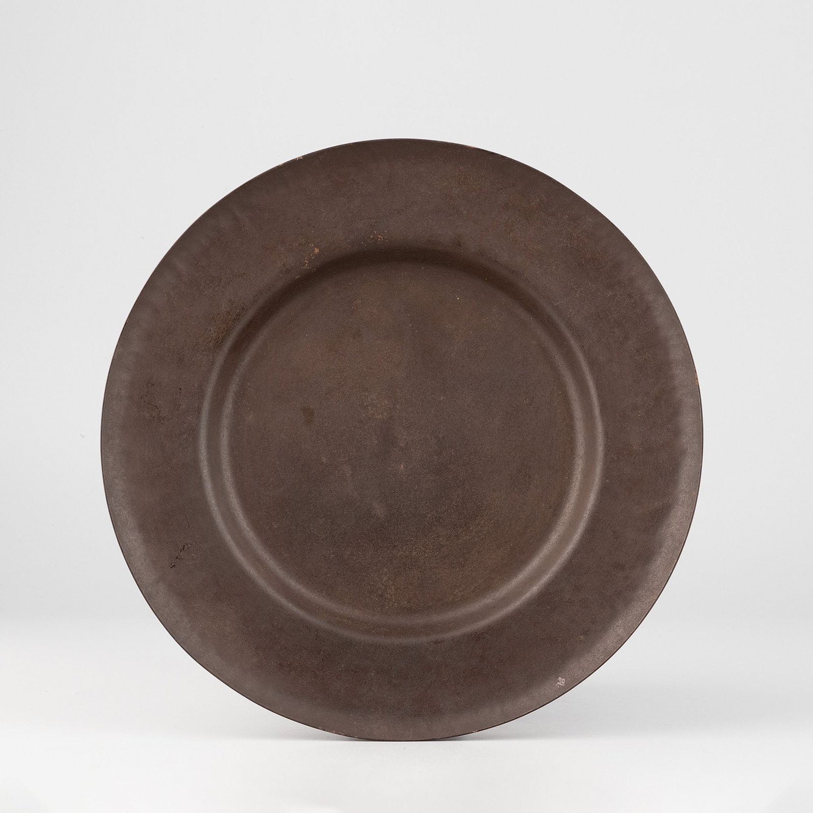 Hammered Iron Tray by Tetsudo Sozen, Tomobako: Formed from a single sheet of iron, the broad circular silhouette is enriched by a finely hammered surface, producing a restrained texture that enhances the natural character of the material. The warm