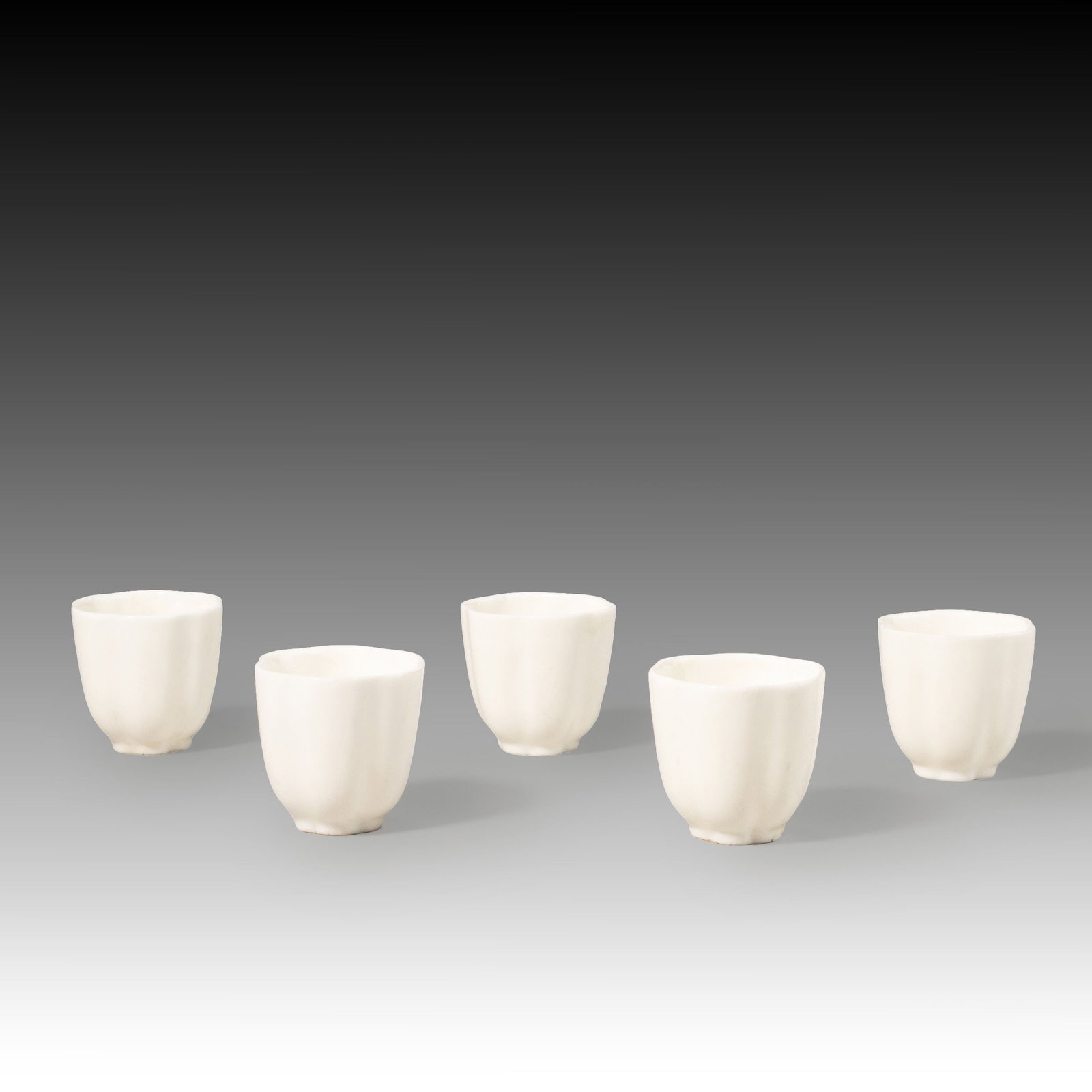 Five White Porcelain Tea Bowls: This set comprises five Dehua white porcelain tea cups of elegant and restrained form. Each cup features a gently tapered rim, rounded body, and low foot ring, with clean, harmonious proportions and r