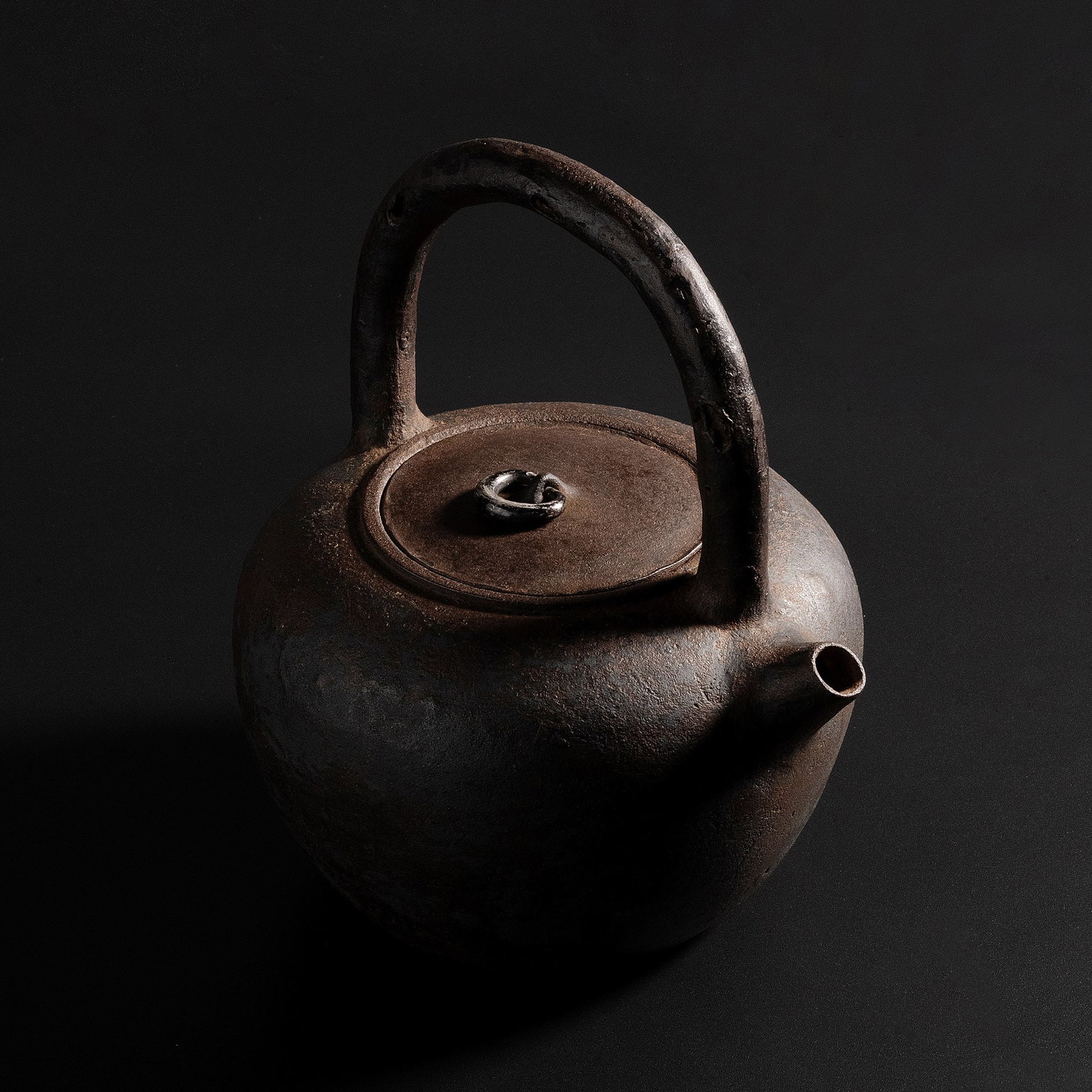 Iron Kettle by Okuni Hakusai, Hakogaki: Inspired by the restrained elegance of ancient earthenware, this iron teapot presents a timeless silhouette distinguished by its rounded body and boldly arched handle. Free from excessive ornamentatio