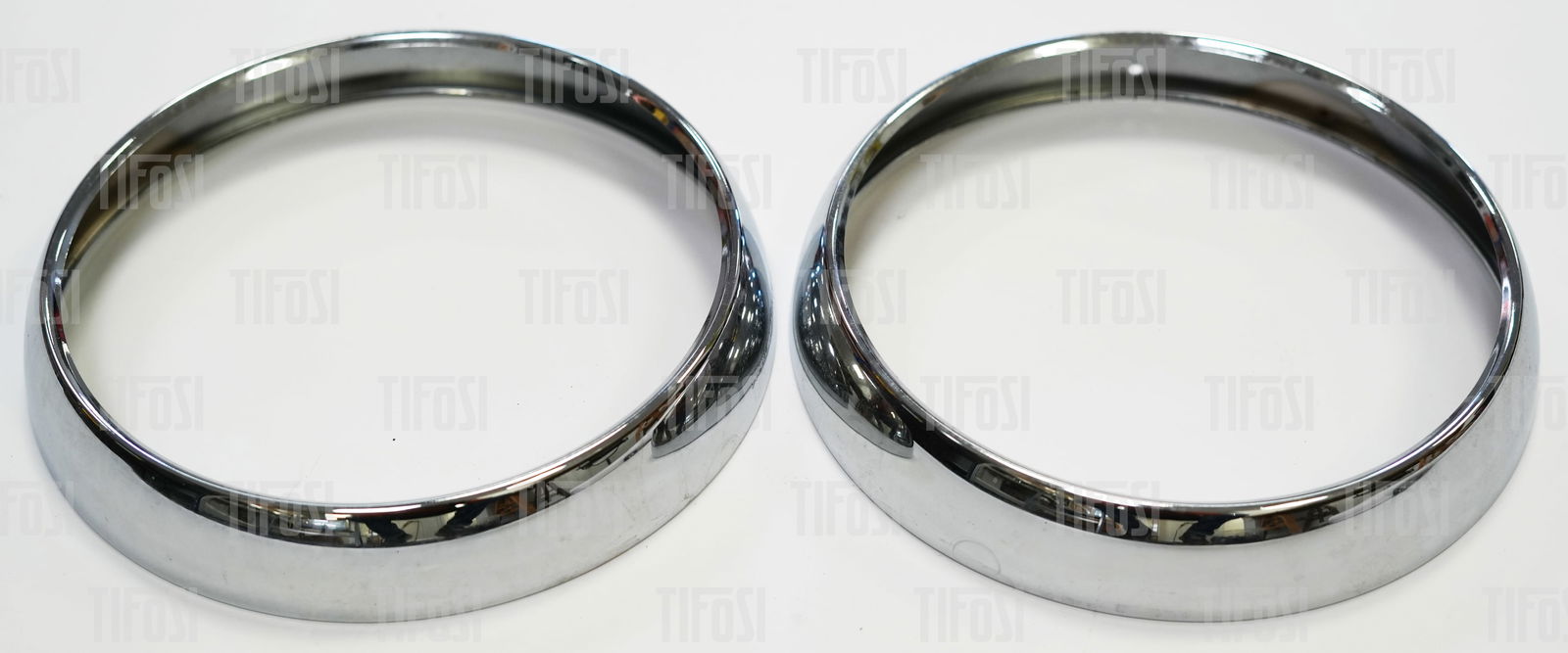 Ferrari 246 Dino NOS Headlamp Chrome Trims: A pair of new old stock headlamp trims to suit Ferrari 246 Dino cars. Carello insignia stamped on both pieces, perfect condition.
