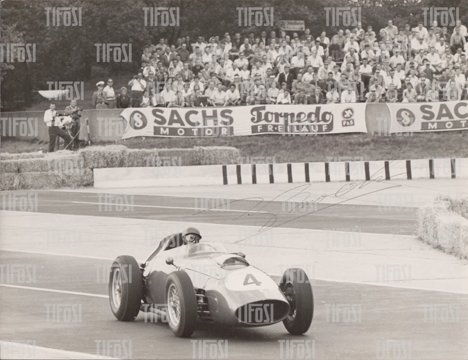 1959 Ferrari 246 Dino F1 Tony Brooks Signed Photograph: An original photograph of Tony Brooks in his Ferrari 246 Dino at the 1959 German Grand Prix, bearing an authentic pen autograph from Brooks. Good condition, 21.5x16.5 CM.
