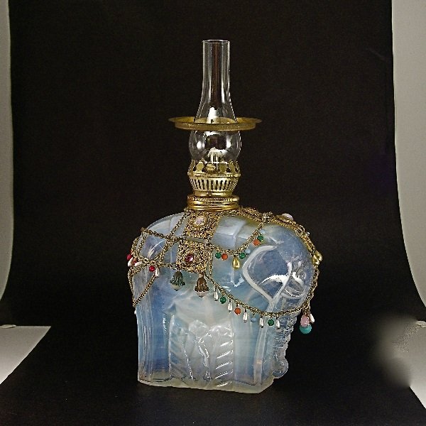 1920s M. Model Opal Glass Oil Lamp / Elephant: 40. 1920s M. Model vanity lamp in opalescent crystal, with jeweled metal ornament, oil lamp fittings, glass chimney. Signed M. Model. 9 1/8 in.