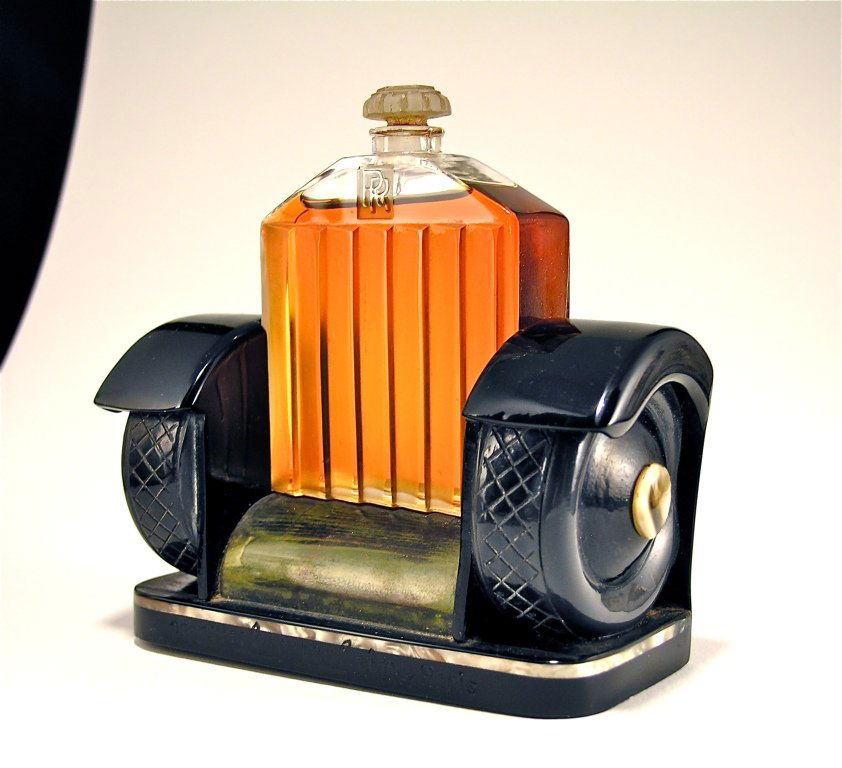 1926 Marcel Guerlain Rolls Royce Perfume Bottle: 1926 Marcel Guerlain Rolls Royce perfume bottle and stopper, clear/frost glass, presented on stand of celluloid, Bakelite, pearl, and wood. Bottle 3 1/4 in.