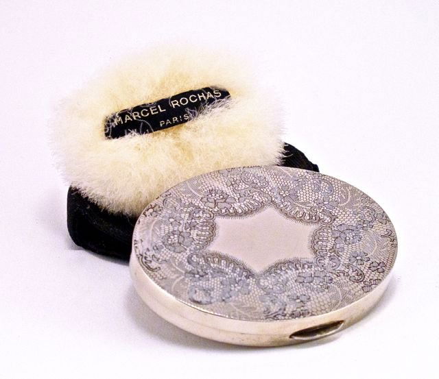 1940s Marcel Rochas Femme compact, silvered metal, impr: 1940s Marcel Rochas Femme compact, silvered metal, impressed design, bevel mirror, puff, suede case. 3 1/2 in.