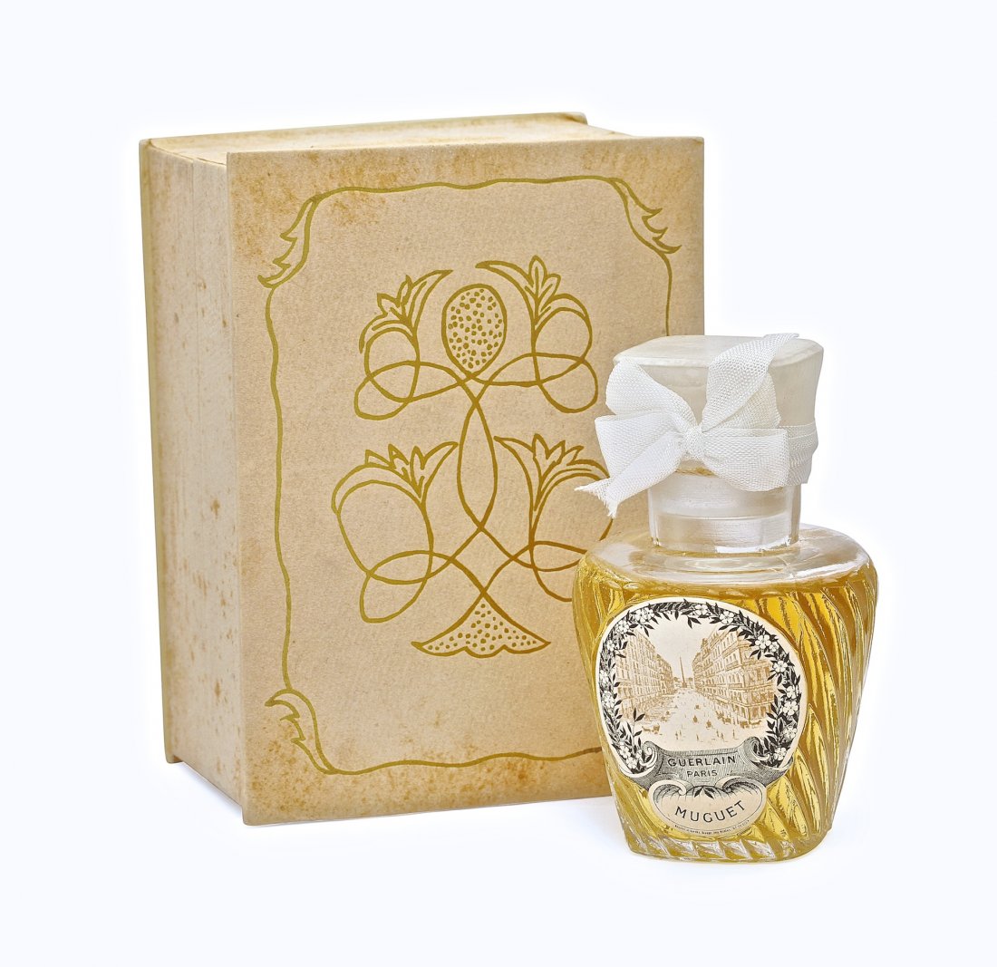 c 1920 Guerlain Muguet perfume bottle: c 1920 Guerlain Muguet perfume bottle and stopper, clear glass, cord, onionskin seal, ribbon decoration, paper label, box. 3 3/4 in.