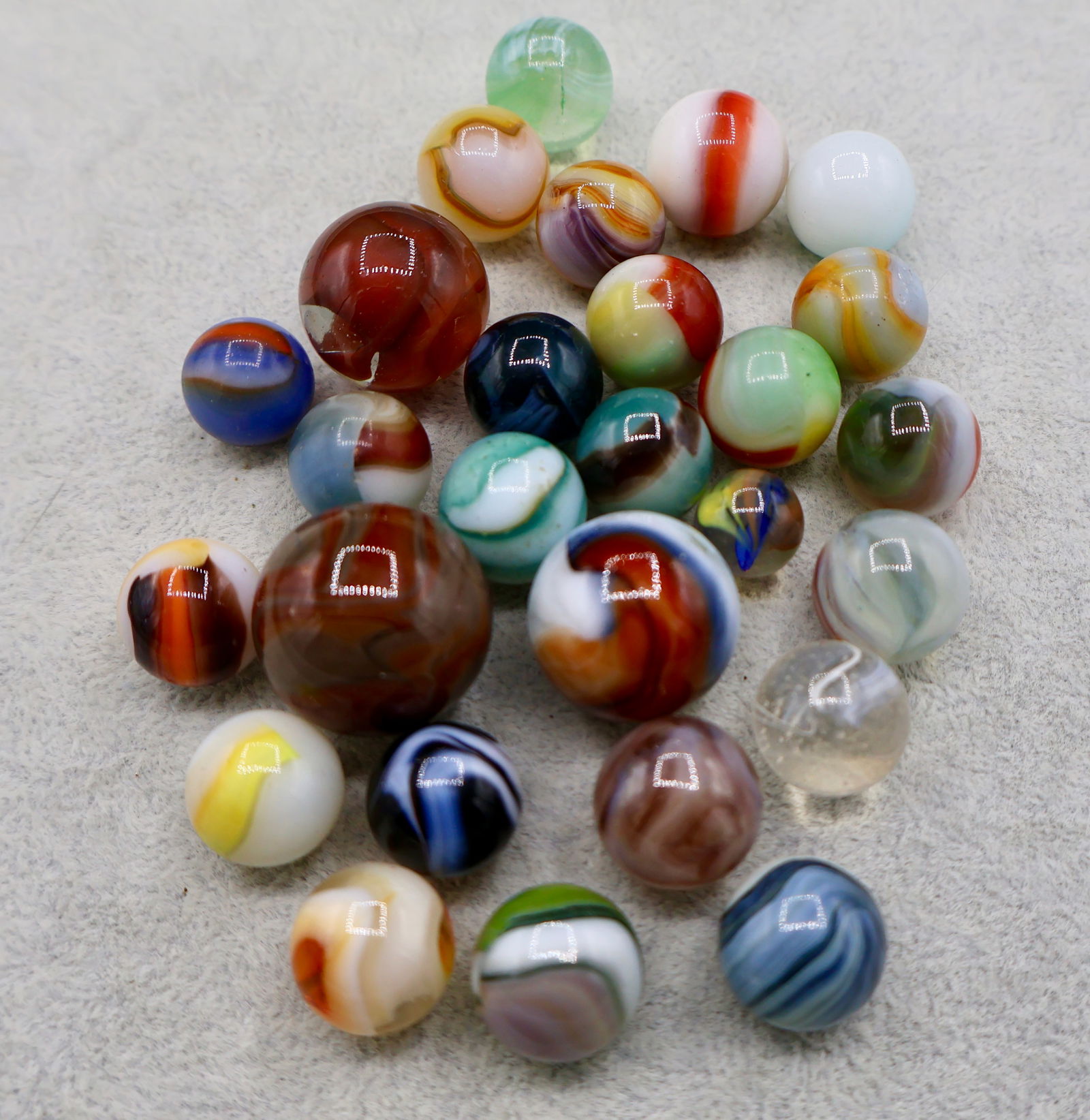 A Grouping of Various Vintage Marbles: Various makers. Various Types like swirl, agate, flame and patch. Various conditions. A variety of vintage marbles from a lifelong collection. Average size 5/8” to 1”. Lot 53