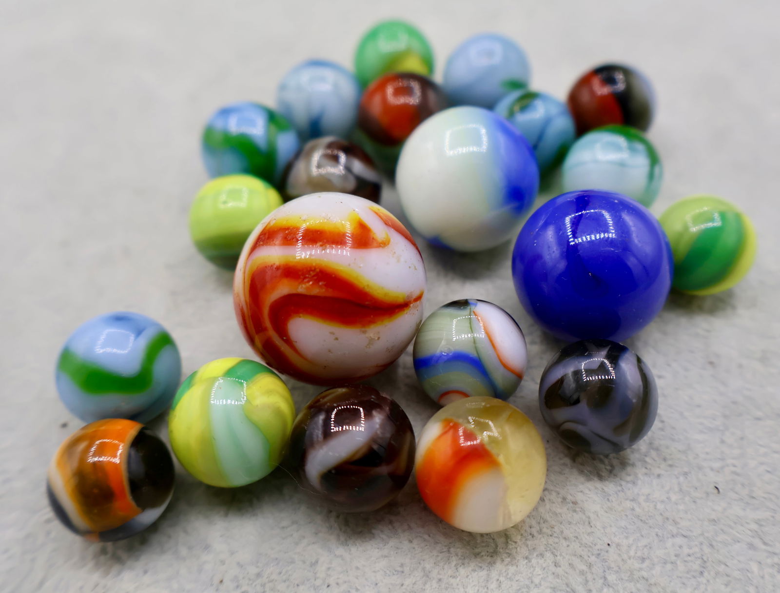 A Grouping of Various Vintage Marbles: Various makers. Various Types like swirl, agate, flame and patch. Various conditions. A variety of vintage marbles from a lifelong collection. Average size 5/8” to 1”. Lot 67